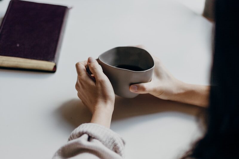 woman in white sweater holding black round frame